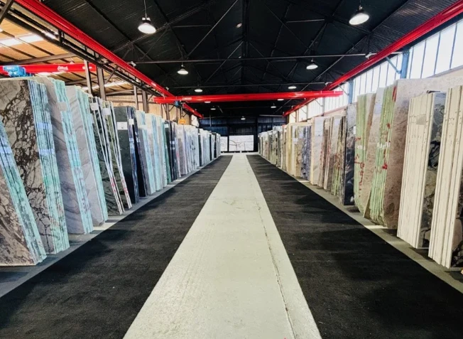 The Cav'art Designer Stone warehouse in Bankstown, with rows of natural stone slabs either side of the aisle